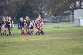 Lady Redbacks’ under 14s Lexey Hoober is dwarfed by her opposition as she is tackled while handballing. 