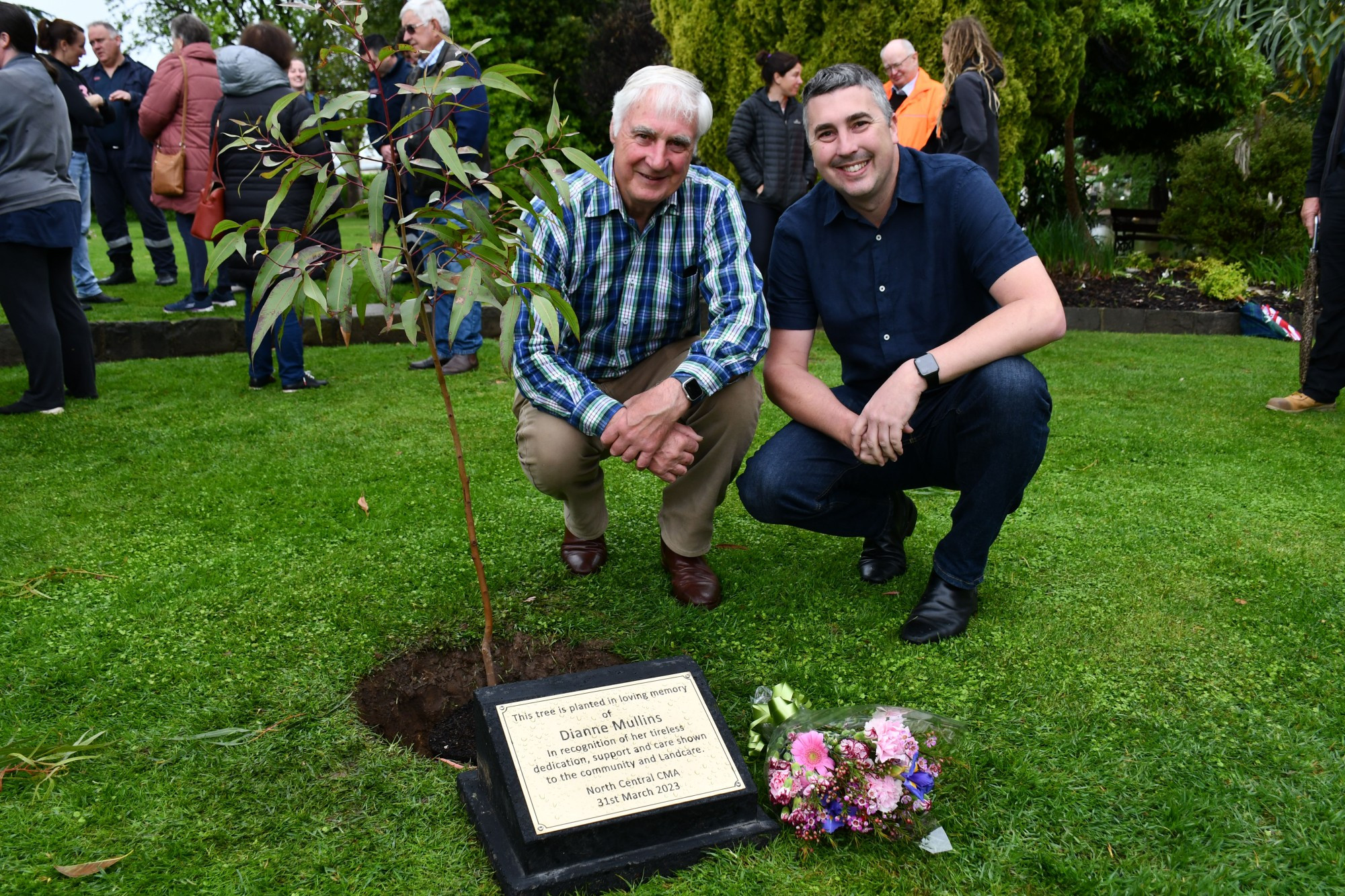 Di’s son James and husband Dan with the new tree and plaque at Phillips Gardens. Photo: 061023 08