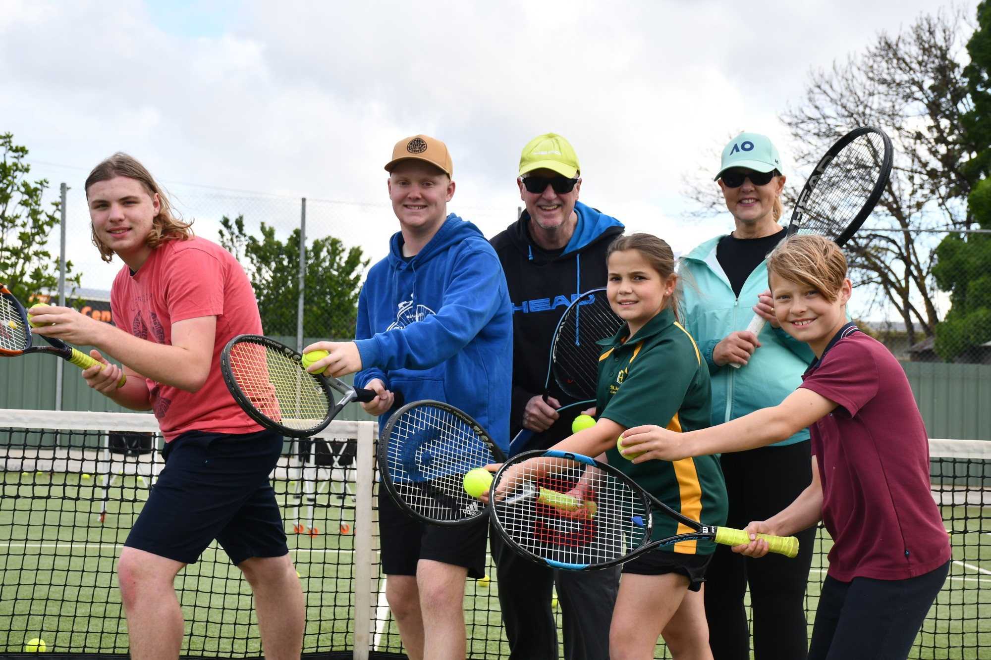 Tennis students Thomas, Ryan, Georgina and James are ready to roll for the summer of sport with program coordinators Brian and Heather Carr (back). Photo: 101023 11