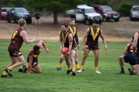 Lachlan Ratcliff looks to clear for Talbot, with a sea of brown and yellow jumpers around him. 