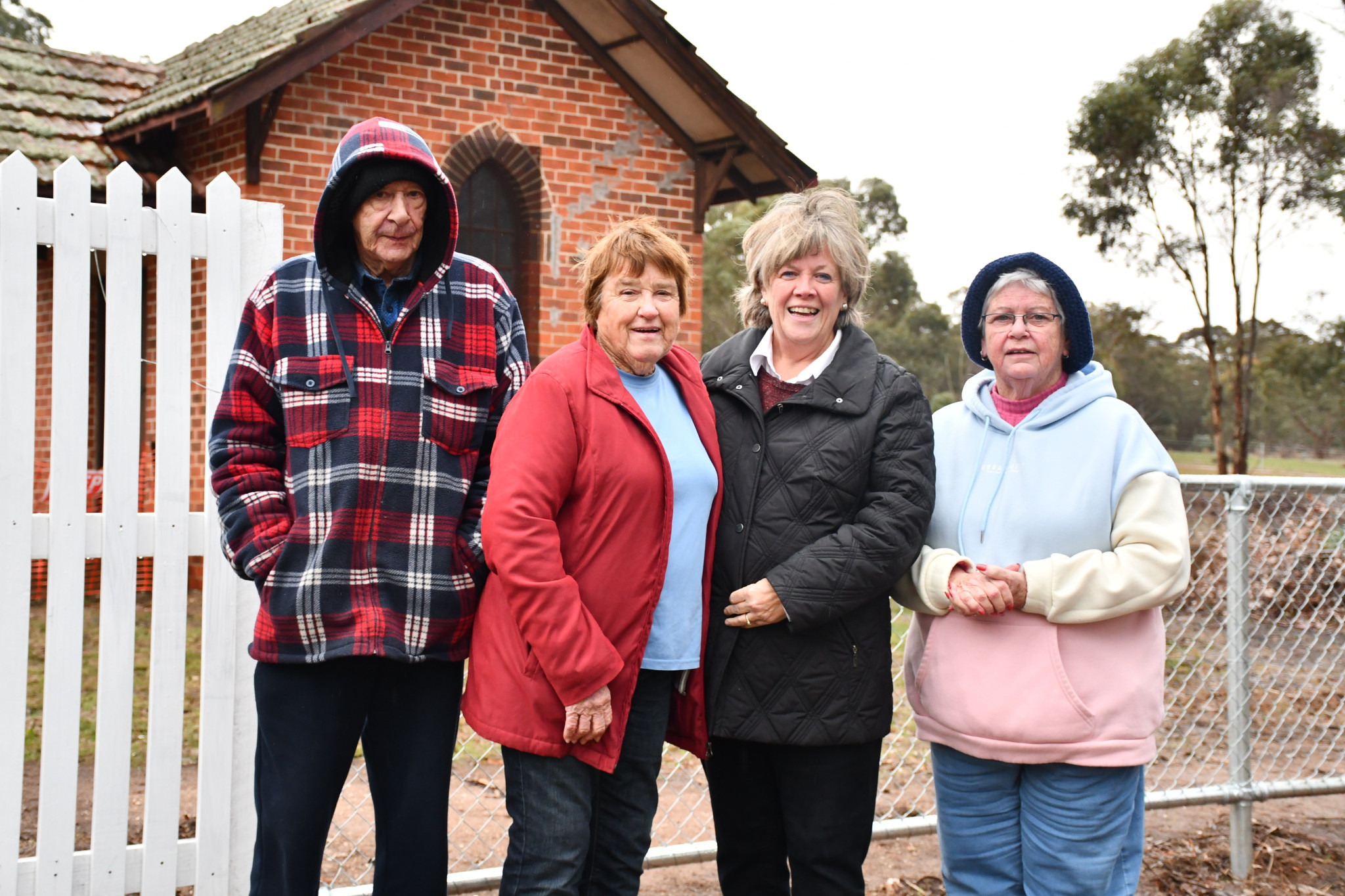 Despite the wet weather, Kevin Hudson, Aileen Howard, Anna De Villiers, and Patricia Rainbow were keen to celebrate the improved fence. Inset: Preserved from the original fenceline, this concrete post preserves the names of the Majorca Cemetery Trust from the early 20th century. 270625 04, 05