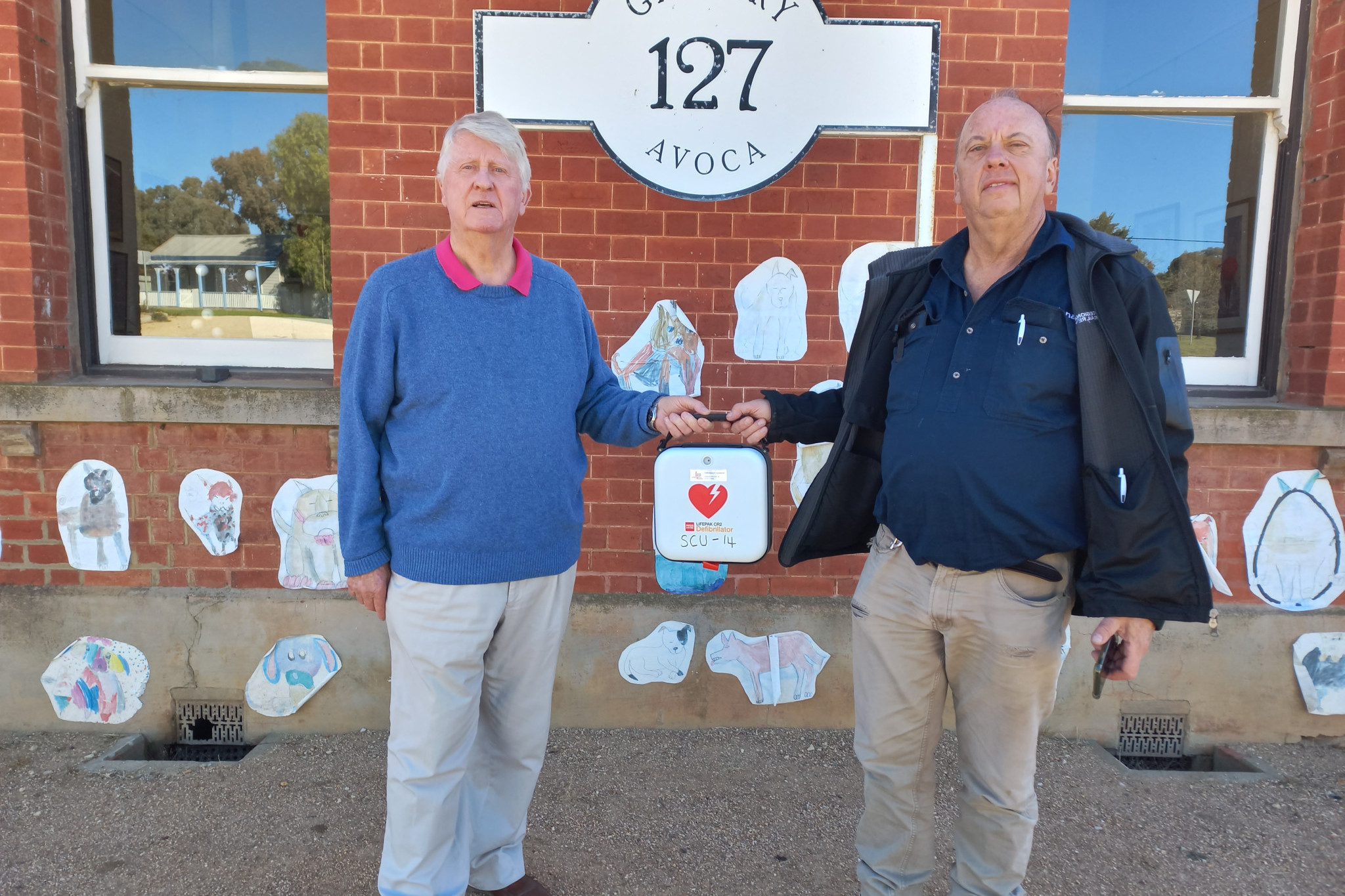Gallery 127’s Hugh Forster accepted an AED donation, which may one day save a life, from Murray Basin Rail Project’s Max Berry last month. Photo: Supplied.